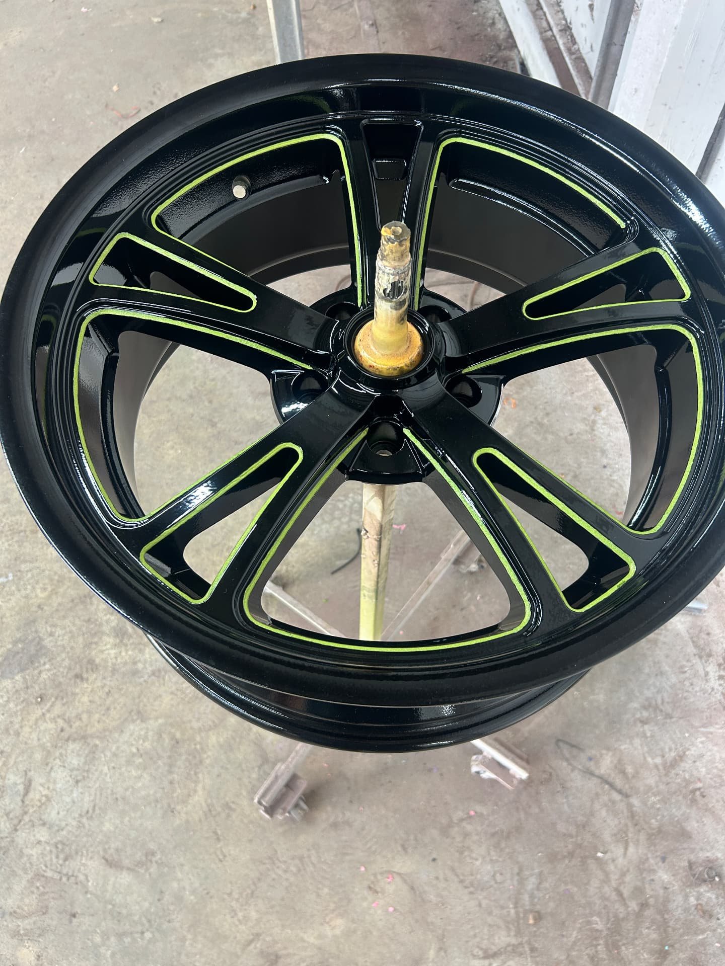 Gloss black powder-coated wheel with lime green pinstripes by Nipper's Powder Coating