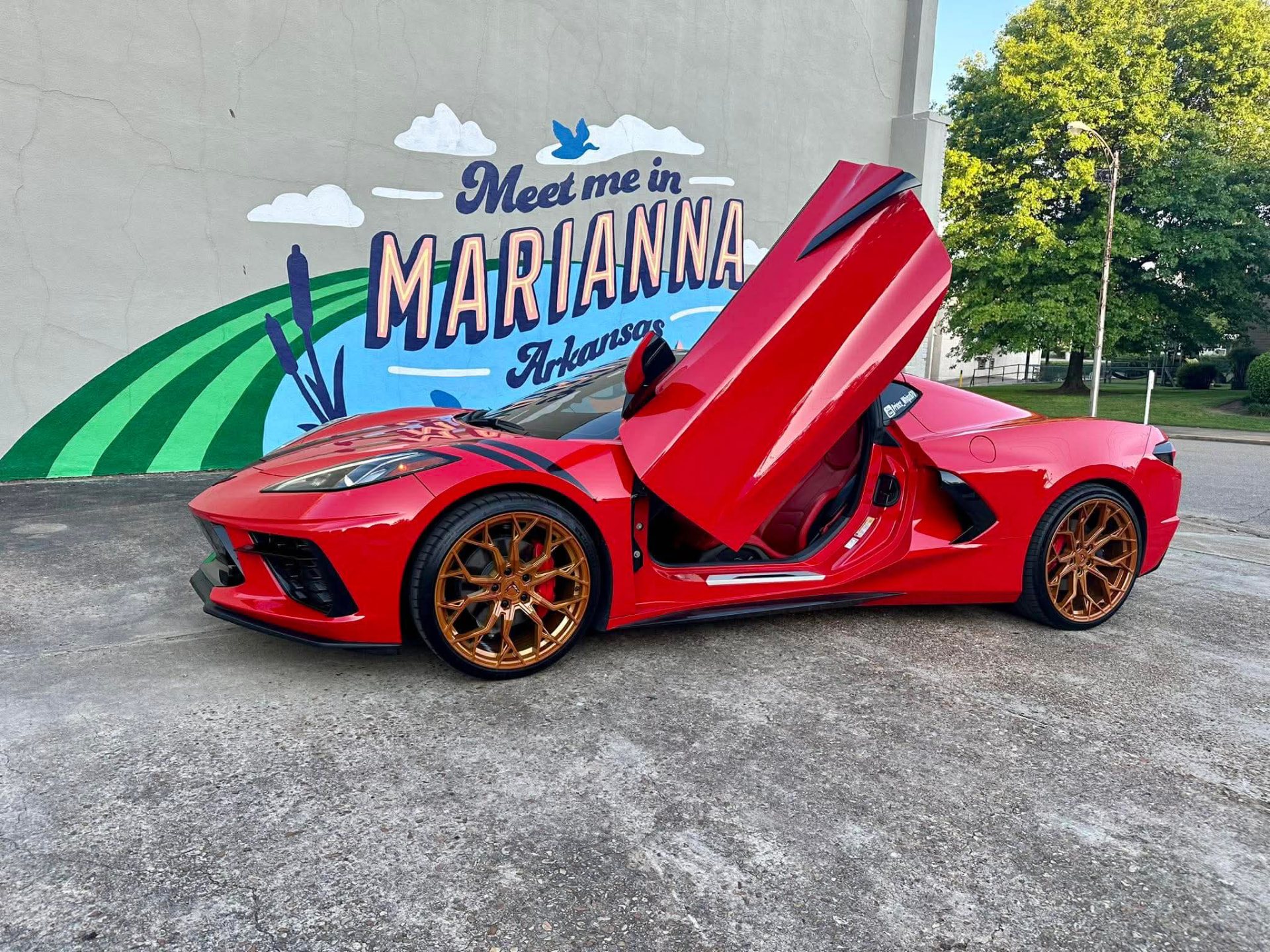 Customer's red car with copper powder-coated wheels by the Meet me in Marianna Arkansas mural